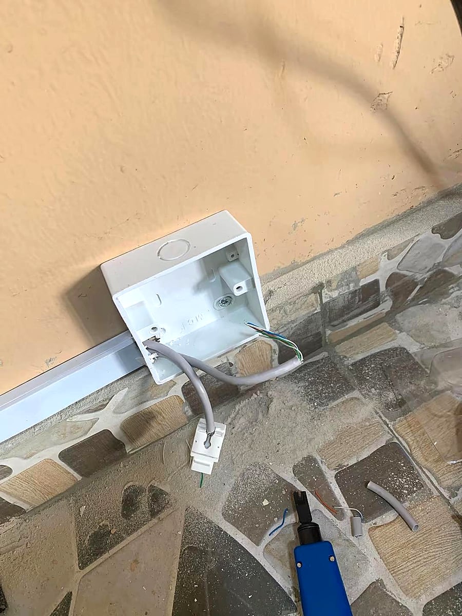 Network cable termination work at a wall outlet.